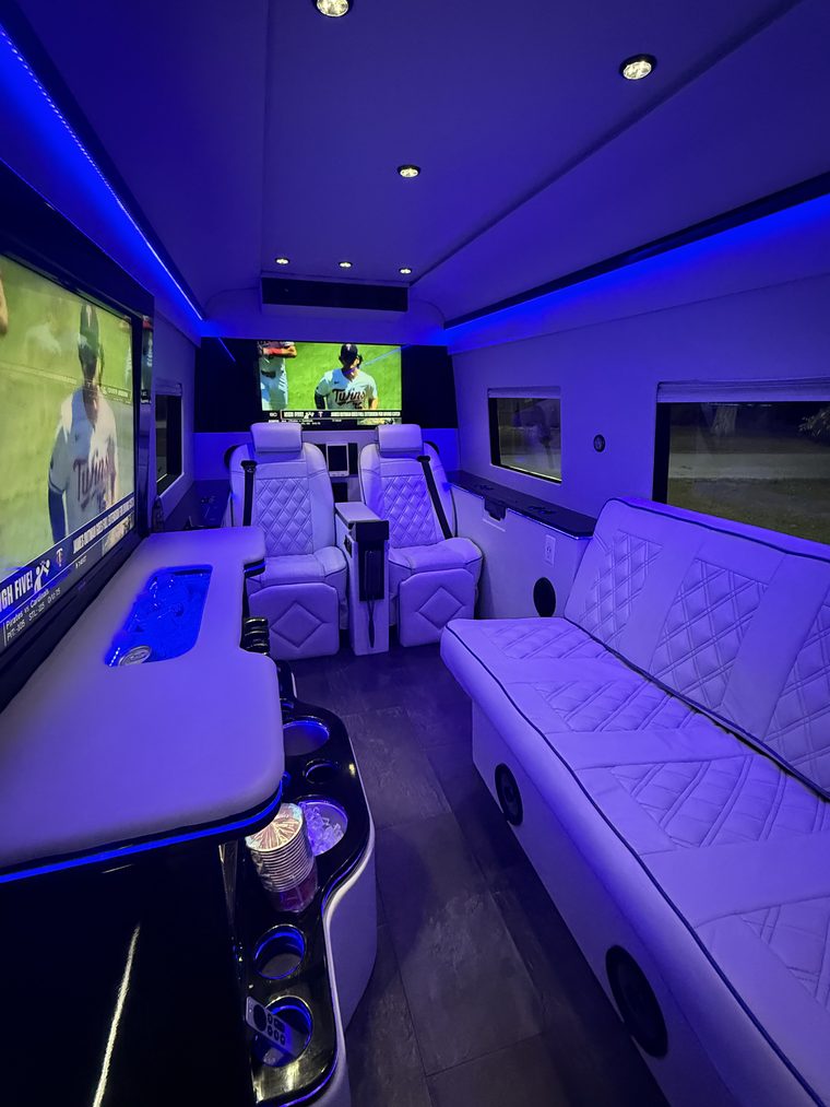 Blue-lit party cabin with the game on the screens and drinks on the bar